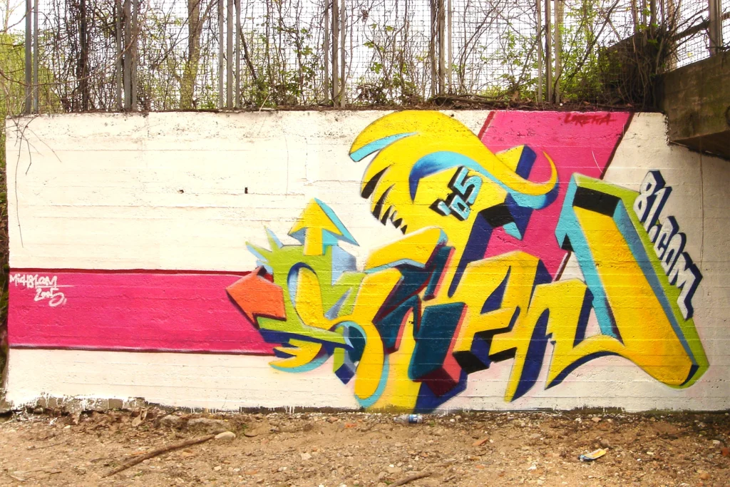 Graffiti tridimensionale con frecce e colori vivaci su muro esterno a Tradate, 2005.