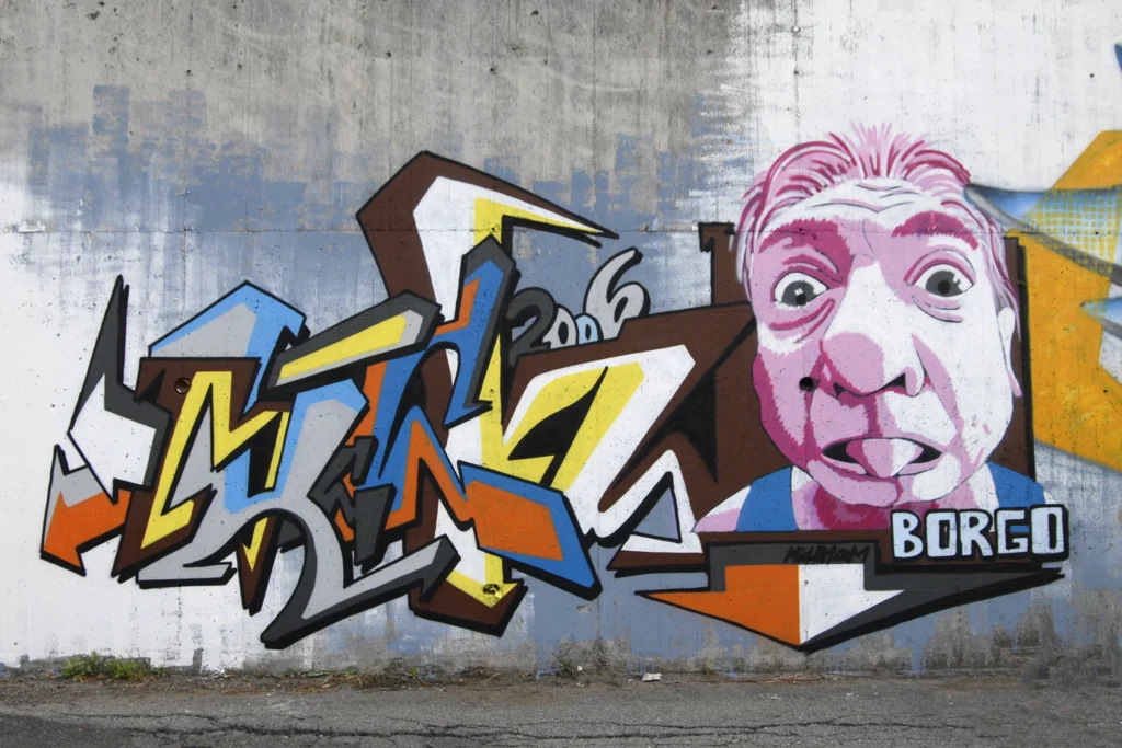 Murale con lettering tridimensionale e ritratto espressivo su muro urbano a Borgo Ticino, 2006.