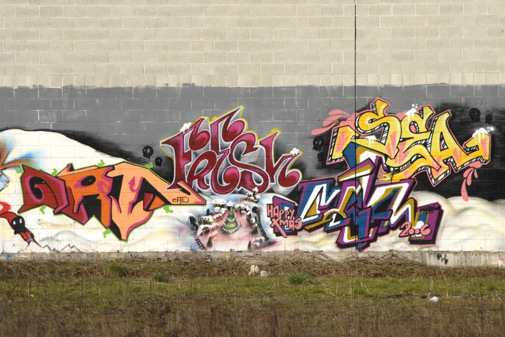 Grande murale con graffiti colorati e scritte sovrapposte su muro industriale, Busto Arsizio 2006.