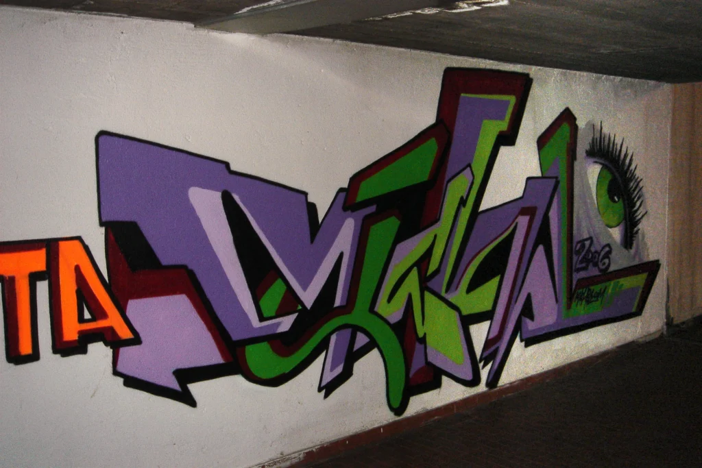 Graffiti verde e viola con occhio realistico su muro di passaggio pedonale, Castiglione 2006.