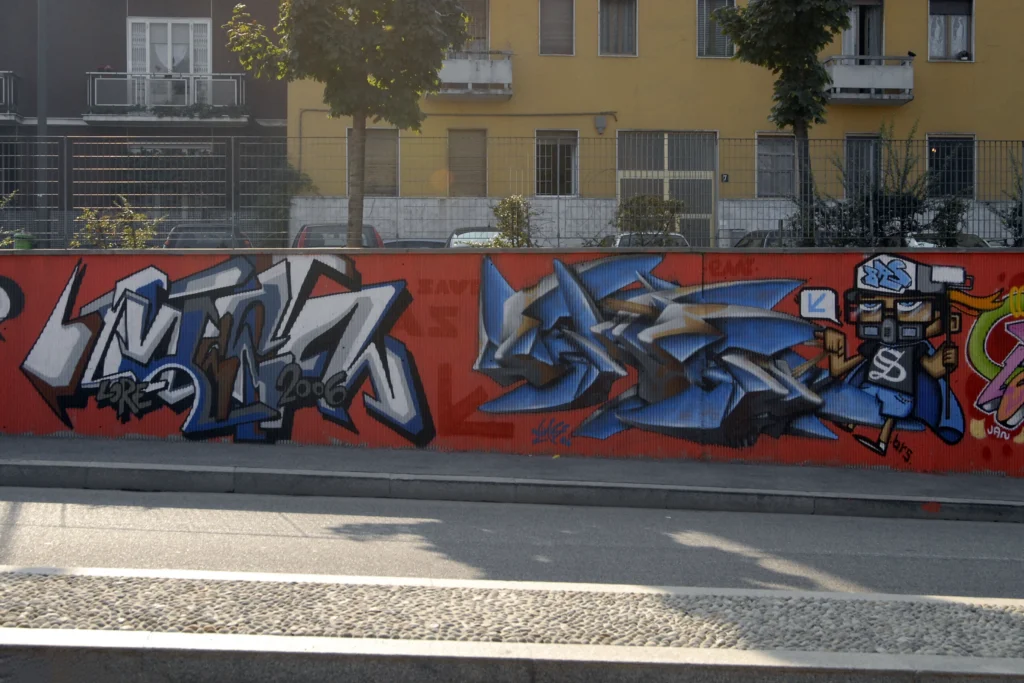 Murale con graffiti blu e bianco e personaggi illustrati su parete rossa, Milano 2006.
