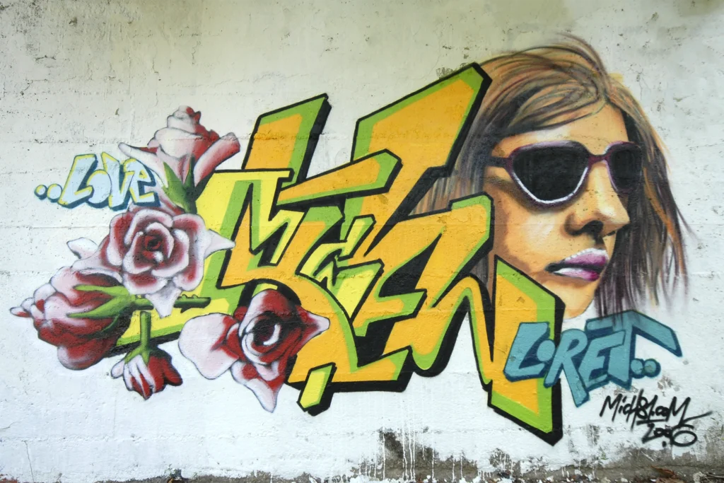 Murale con lettering giallo-verde e ritratto realistico di donna con occhiali, Tradate 2006.