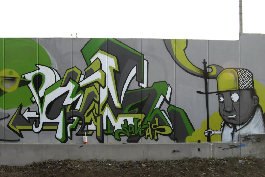 Murale con lettering verde e grigio e personaggio illustrato monocromo, Castelletto Sopra Ticino 2007.