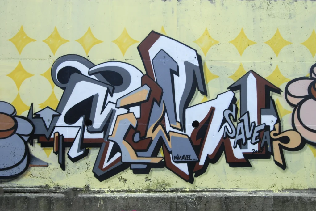 Murale con lettering bianco e marrone su sfondo giallo con pattern a stelle, Tradate 2007.